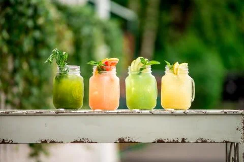 Lemonade grape kiwi pineaple lime and banana on terrace summer spring table c Stock Photos