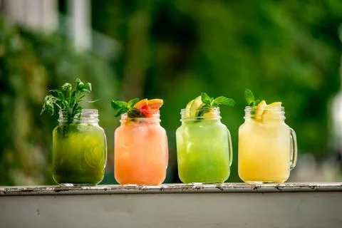 Lemonade grape kiwi pineaple lime and banana on terrace summer spring table c Stock Photos