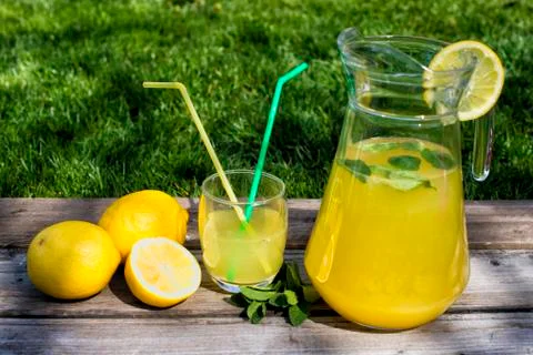Lemonade in the jug and lemons on the table outdoor Stock Photos