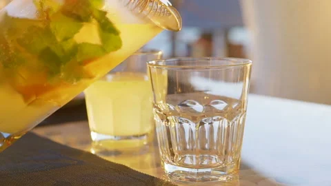 Lemonade with orange, mint and ice pouring into glass Stock Footage 95843848
