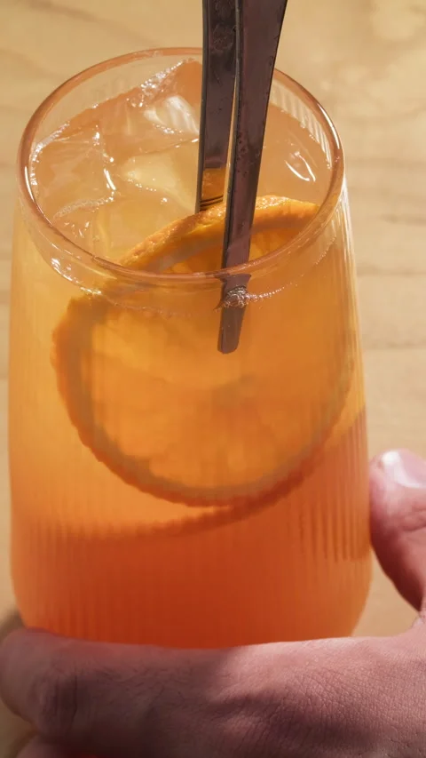 Lemonade with oranges. Garnishing summer soft drink in a glass with sliced fresh Stock Footage 314015998
