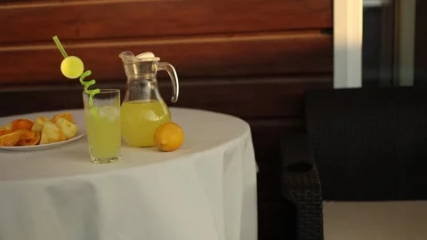 Lemonade pitcher and glass on round table in warm indoor dining setting Stock Footage 337428843
