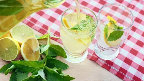Lemonade is poured from a decanter into two glasses Vidéo 89946023