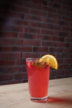 Lemonade on table, mint and lemon wedge, glass with straw, brick wall on Stock Photos