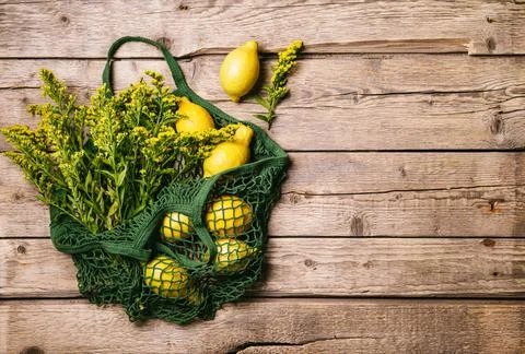 Lemons and flowers in a string bag on a wooden background. Zero waste concept Stock Photos