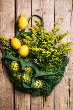 Lemons and flowers in a string bag on a wooden background. Zero waste concept Stock Photos