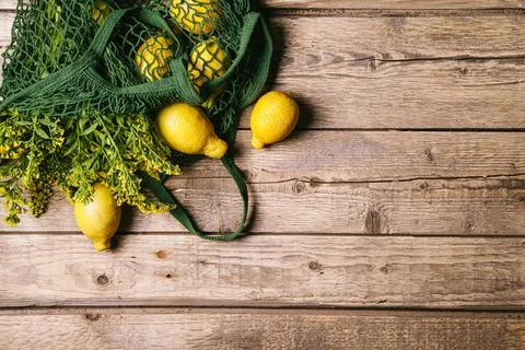 Lemons and flowers in a string bag on a wooden background. Zero waste concept Stock Photos
