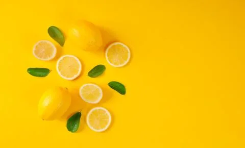Lemons and green leaves on bright yellow background. Food concept, flat lay. Stock Photos