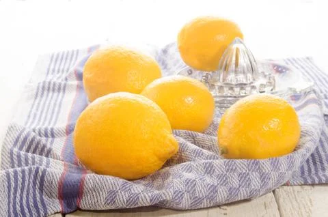 Lemons and lemon squeezer on a kitchen towel Stock Photos