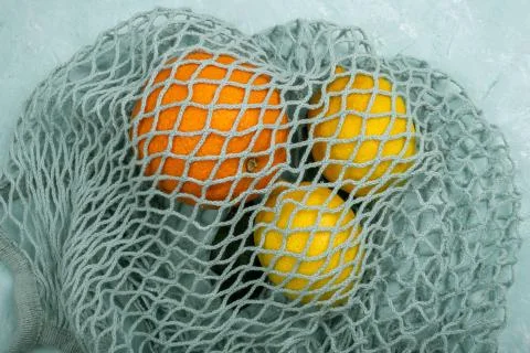 Lemons and orange in blue string bag Stock Photos