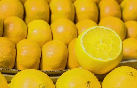 Lemons are placed in a box, with one lemon cut in half to show its bright ins Фото