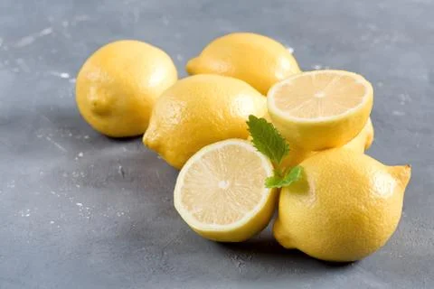 Lemons on cutting board on grey background Fresh yellow citrus Mint leaf Stock Photos