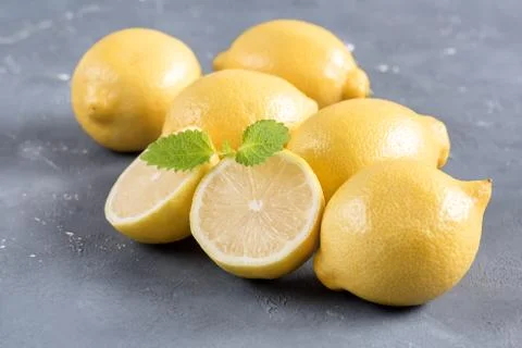 Lemons on cutting board on grey background Fresh yellow citrus Mint leaf Stock Photos
