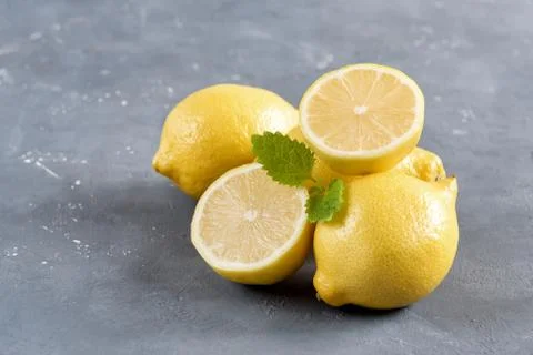 Lemons on cutting board on grey background Fresh yellow citrus Mint leaf Stock Photos