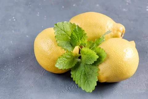 Lemons on cutting board on grey background Fresh yellow citrus Mint leaf Stock Photos