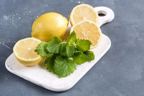 Lemons on cutting board on grey background Fresh yellow citrus Mint leaf Stock Photos