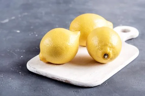 Lemons on cutting board on grey background Fresh yellow citrus Stock Photos