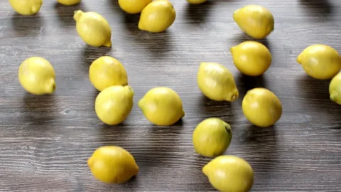 Lemons falling and rolling on a wooden table. Stock Footage 169817828