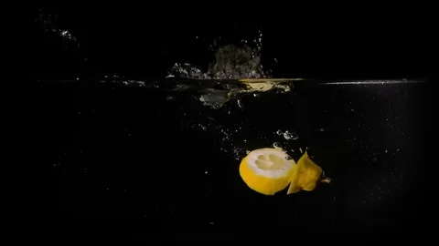 Lemons falling in the water on black background. Slow motion 1080p clip. Stock Footage 80759732