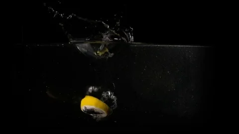 Lemons falling in the water on black background. Slow motion 1080p clip. Stock Footage 80759749