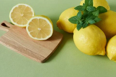 Lemons, mint and cutting board on a green background. Stock Photos
