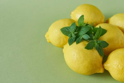 Lemons with mint leaves on green background. Close up. Stock Photos