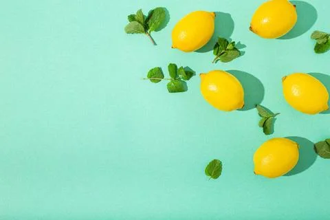 Lemons with mint on minimal blue background sun light hard shadows pattern... Stock Photos
