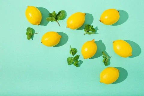 Lemons with mint on minimal blue background sun light hard shadows pattern... Stock Photos