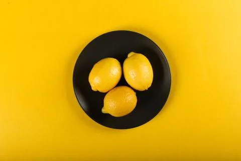 Lemons in a plate on a yellow background Stock Photos