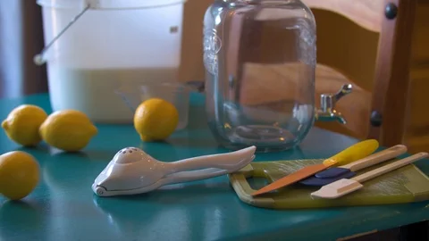 Lemons Rolling Across a Table in front of Lemonade making Utensils Stock Footage 94394863