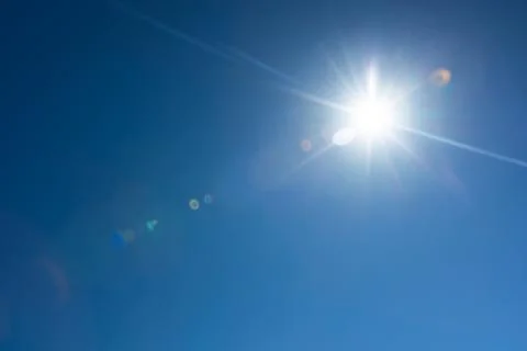 Lens flare effect over deep blue sky with sun Stock Photos
