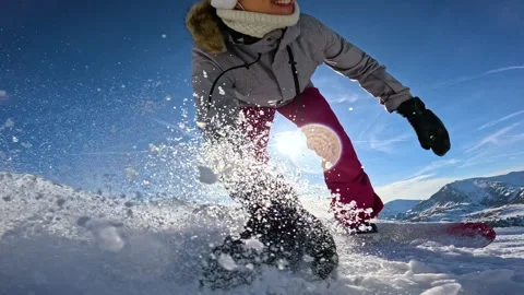 LENS FLARE, LOW ANGLE VIEW, SLOW MOTION: Smiling woman snowboards toward camera Stock Footage 324597888