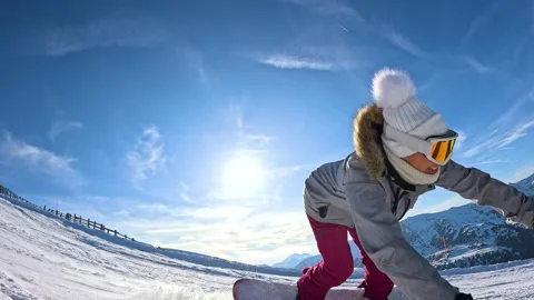 LENS FLARE, LOW ANGLE VIEW, SLOW MOTION Smiling snowboarder leans towards camera Stock Footage 324598155