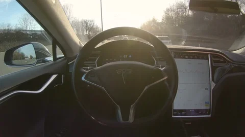LENS FLARE: Modern electric car with no human driver drives along busy motorway. Stock Footage