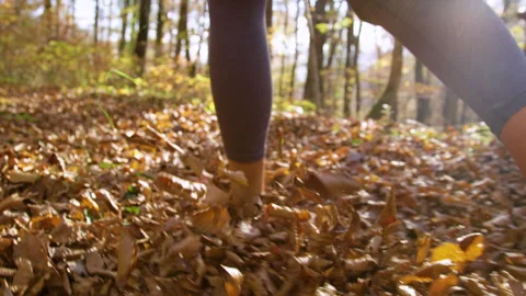 LENS FLARE, SLOW MOTION, CLOSE UP, DOF: Person running barefoot in autumn forest Stock Footage 317581530