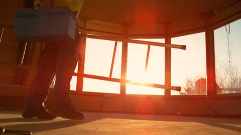 LENS FLARE Worker coming to work carries his toolbox and ladder across the room. Stock Footage 124692860