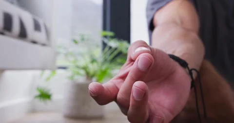 Lens focusing on hand, man rotating, pressing palms together by window, plant, Stock Footage 338168540