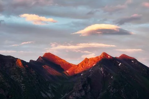 Lenticular cloud over a mountain peak in the setting sun Stock Photos
