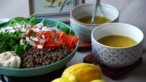 Lentil salad on rotating platform Creating a salad adding hummus to plate Stock Footage 259156302