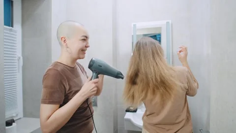 Lesbian couple in a bathroom having fun while drying hair together during a casu Stock Footage 346152165