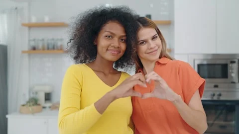 Lesbian couple doing heart shape symbol with hands,smiling and looking at camera Stock Footage 246533096
