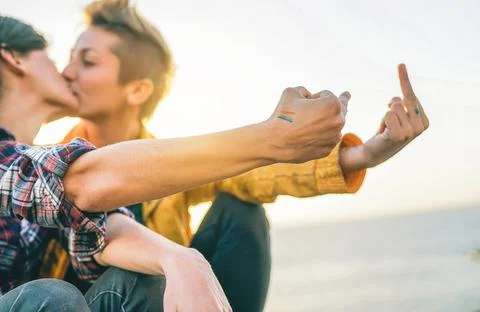 Lesbian couple kissing at sunset - Gay having a tender moment on the beach Stock Photos