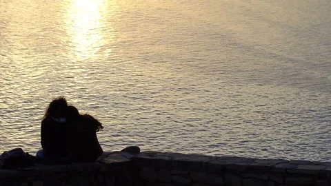 Lesbian couple sitting on the bench, looking at sunset Stock Footage 84630178
