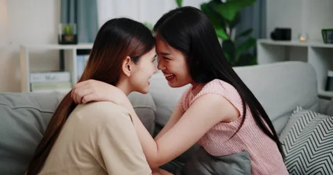 Lesbian couple sitting on sofa sharing good feelings  Stockbeeldmateriaal 293545582