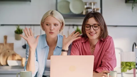 Lesbian pair talking virtual call using computer in kitchen together closeup Stock Footage 335104204