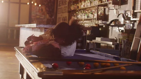 Lesbian partners playing pool at a local pub and kissing on the table Video stock 262556768