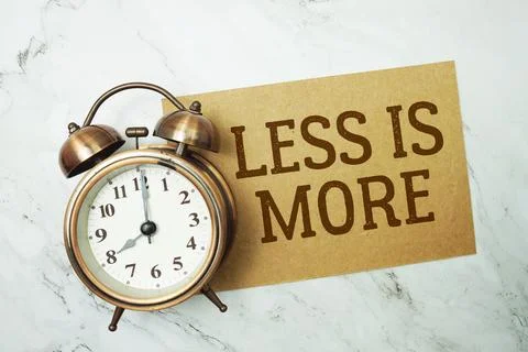 Less Is More text written on paper card with alarm clock on marble background Stock Photos
