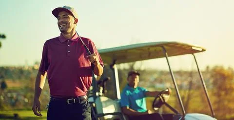 Less work more golf. a golfer holding his club with a buggy blurred in the 스톡 사진