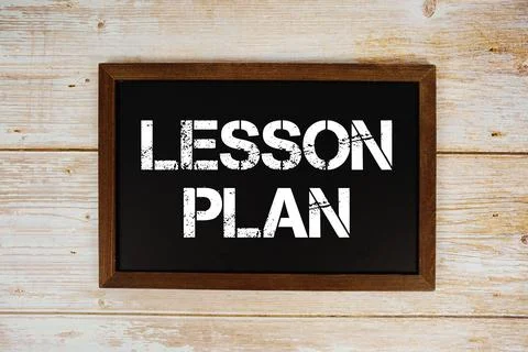 Lesson Plan text with gift box present and alarm clock on black background Stock Photos