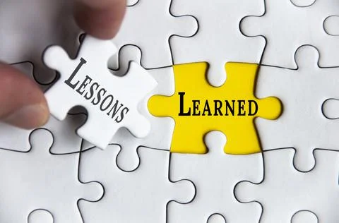 Lessons learned text on Jigsaw Puzzle with one hand holding a missing jigsaw Stock Photos